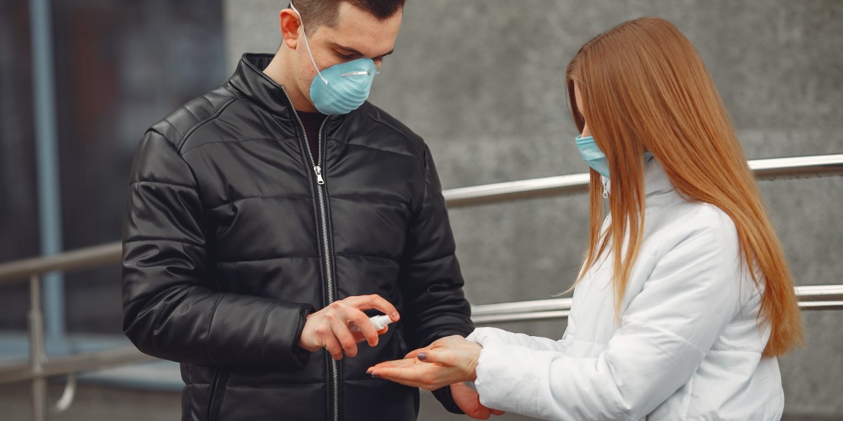 Young people wearing protective masks are spraying hand sanitizer .